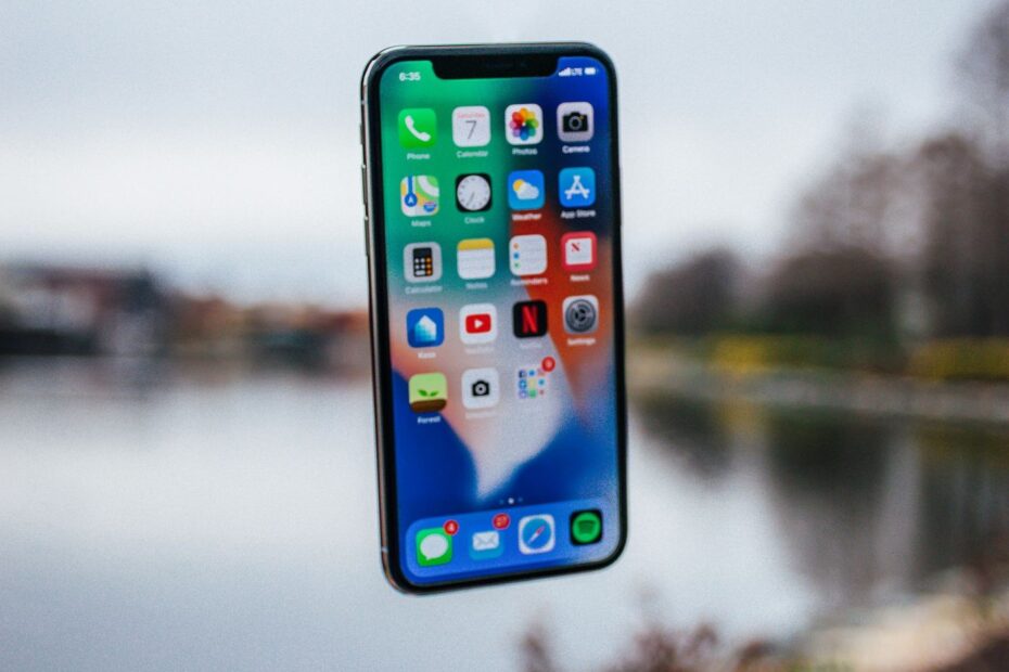 Silver iPhone floating above an open hand
