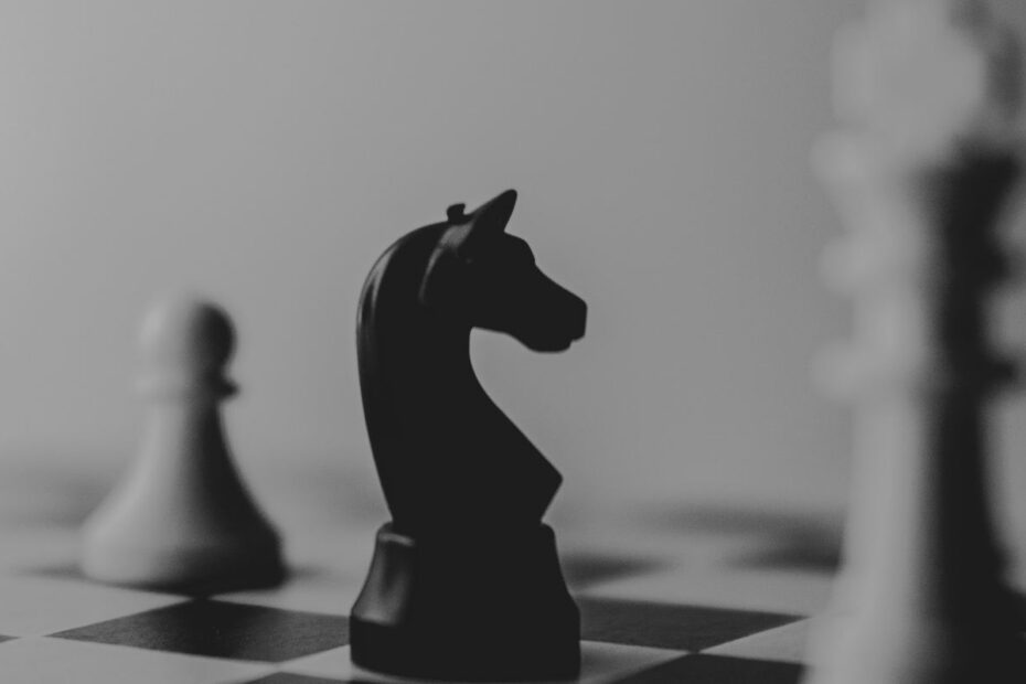 Black chess knight in sharp focus between blurred white pieces on a chessboard, a metaphor for poker strategy choices