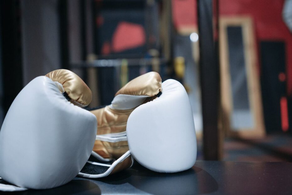 A pair of white and gold boxing gloves resting on a dark surface, a symbol of the one-on-one duel in heads-up poker