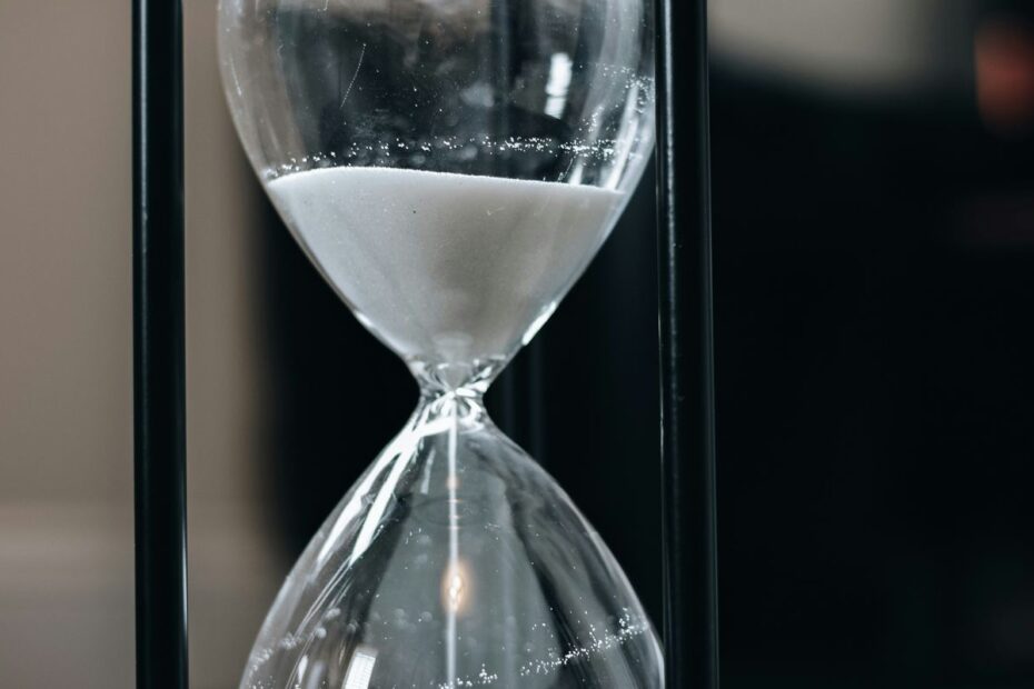 Close-up of an hourglass with white sand running through it, symbolizing rising blinds and time in a poker tournament