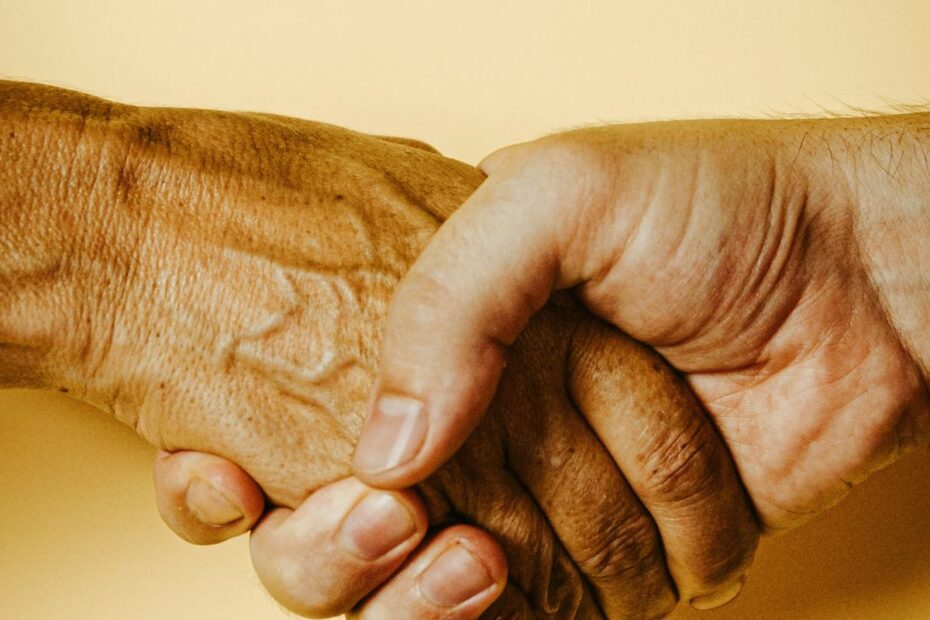 Close-up of two hands in a firm handshake against a warm yellow background, representing good sportsmanship at the poker table